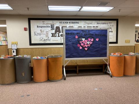 A Bulletin board with daily totals and six filled donation barrels 