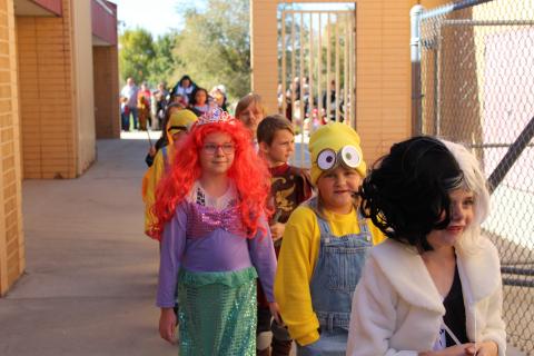 Students in costume walking in the parade past parents