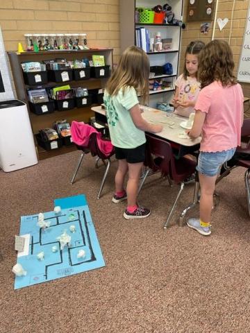 Three students talking and working on obstacles for their maze