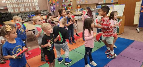 Kindergarten students shaking and dancing with watermelon shakers
