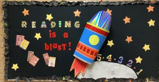 "Reading is a blast!: bulletin board with a rocket and pictures of the Nutritional Specialists when they were children