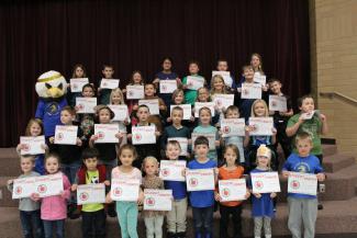 Students holding "Student of the Month" certificates