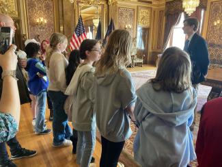 Students standing and listening to a State Legislator