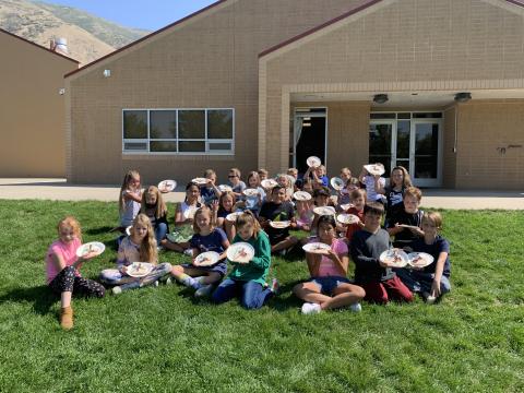 Ms. Huston's class showing off their finished maps outside on the grass