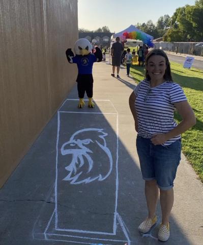 PTA President, Mrs. Furman, standing next to a Chalk art picture of an Eagle and the Eagle Mascot 
