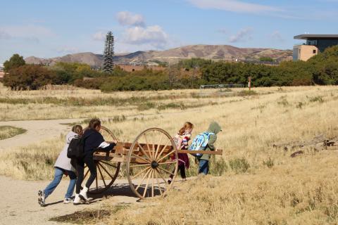 four students pushing and pulling a pioneer handcart