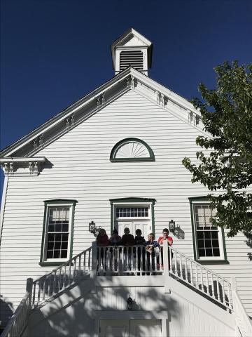Students standing on the porch of a school house