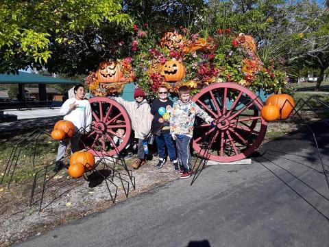 Students standing in front of a wagon that is decorated with fall leaves and pumkins