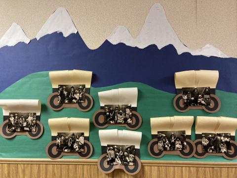 Bulletin Board "Mountain scene" of 5th Grade students in western wear in covered wagons