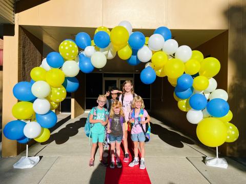 Children standing under a balloon arch 