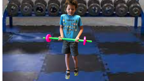 Student lifting a pretend bar bell (in a Green screen work out room)