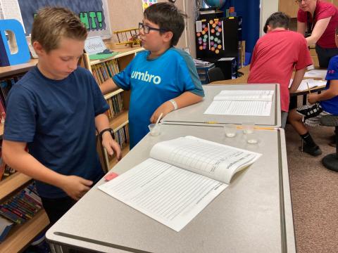Students recording what they are observing in a notebook