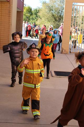 Students in costume walking in the parade past parents