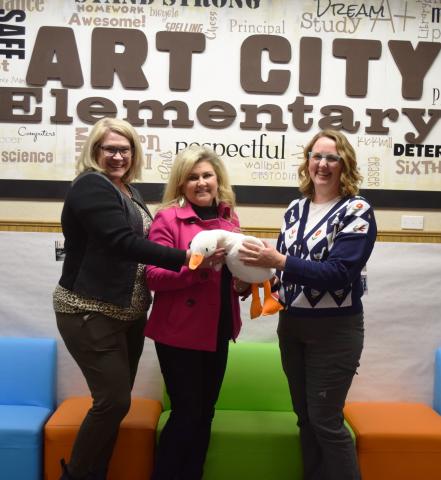 Mrs. Muirbrook, Lana Hiskey, and Samantha Gwilliam holding a stuffed duck in the Art City Elementary Lobby