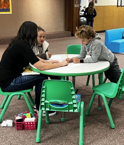 Students sitting with a tutor at the table in the Lobby of Art City Elementary School