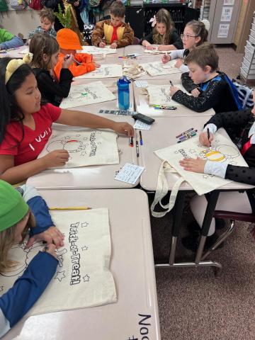 Students in costumes in a rotation at their desks decorating a candy bag