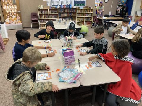Students in costumes in a rotation at their desks playing a game