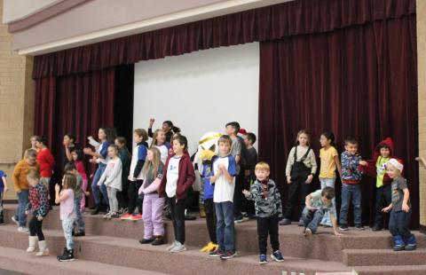 Students dancing on the stage before an assembly with Ace the Eagle