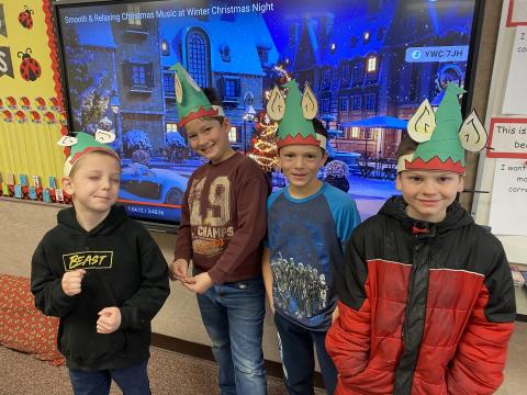 Students dressed like Elves posing in front of a Christmas scene. 