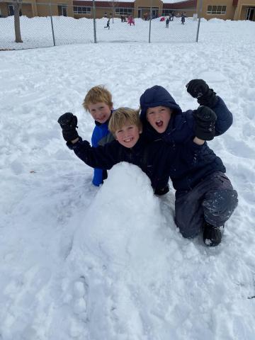 Three students playing in the snow