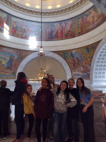 students standing in front of some of the murals of the Capitol 
