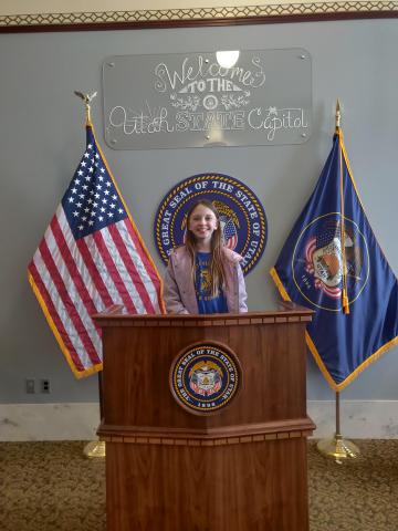 Student standing at a pulpit in the Capitol building 