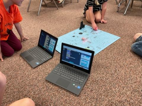 chrome books showing the code as students watch their Ozobot traverse a maze