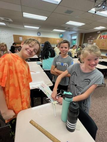 Three students creating a bridge with straws
