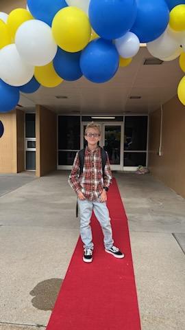 A student on the red carpet under the balloon arch