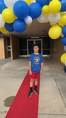 A student on the red carpet under the balloon arch