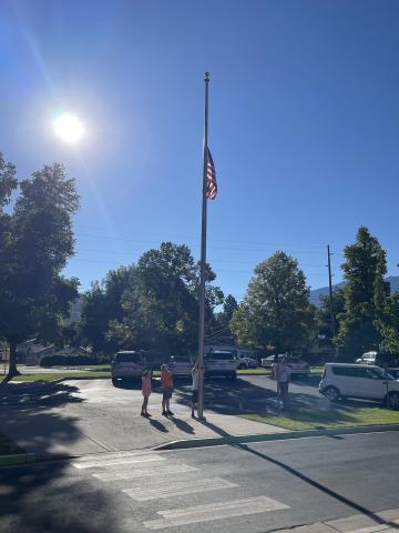 Three fifth-grade students lowering the flag to half staff