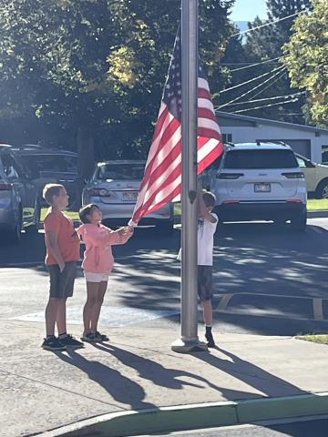 Three fifth-grade students raising the flag