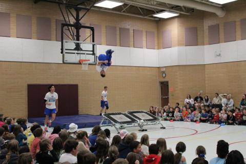 BYU Dunk team "flying" through the air as students cheer them on. 
