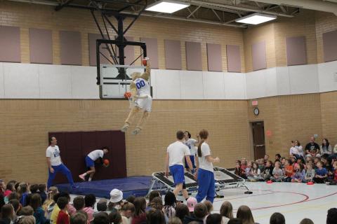 Cosmo"flying" through the air as students cheer them on. 