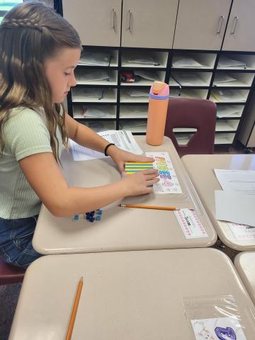 One student sitting at her desk using math manipulatives