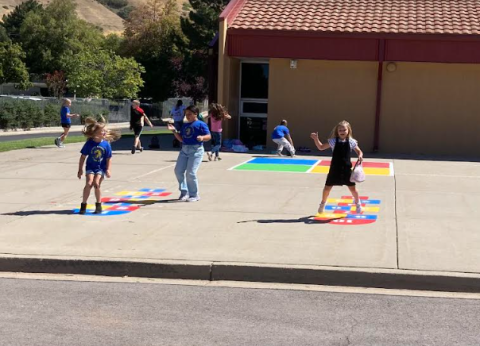 Students playing on the newly refurbished hopscotch and in the background the four square game. 