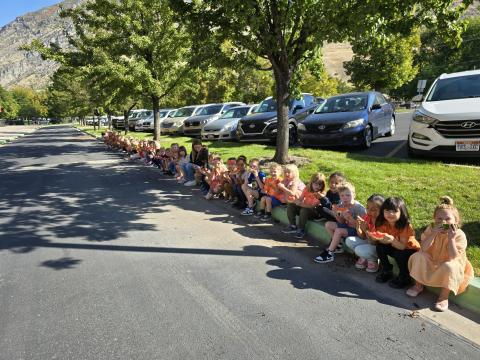 Kindergarten students sitting on the curb eating fresh watermelon