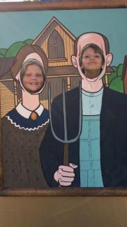 Two students in a photo prop of Edward Munch's American Gothic (Ma and Pa in front of the farm house