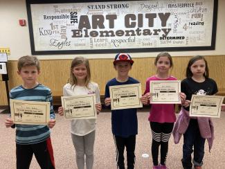 Three girls and two boys holding their certificates for placing in the third-grade track meet