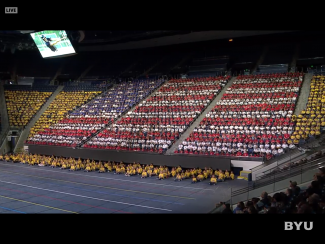 An American flag made up of students and teachers wearing different colored shirts