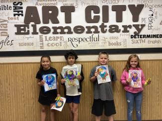 Four Students holding their art work 