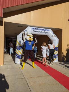 ACE the Eagle greeting students on the red carpet as they walked the red carpet and went through the Art City Elementary arch